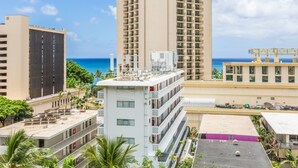 A high-rise building with multiple balconies, a rooftop pool, and a view of the ocean.