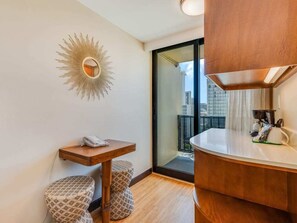 Une salle de bain moderne avec un meuble-lavabo en bois, un miroir en forme de soleil et une vue sur la ville, visible à travers une porte en verre.