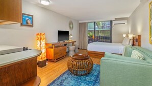 Une chambre d’hôtel moderne avec un bureau en bois, un lit, un canapé et un balcon offrant une vue.