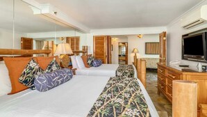 A hotel room with two beds, a television, a mirror, and a wooden dresser.