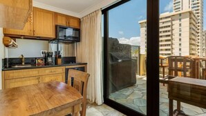 A modern kitchen with wooden cabinets, a microwave, and a dining area with a table and chairs.
