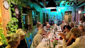 A dining area with tables set for a meal, surrounded by green plants and artwork on the walls. - Mediterranean apartment of Guesthouse In de Aap - Finca - Hartje Bergen (Bergen (NH))