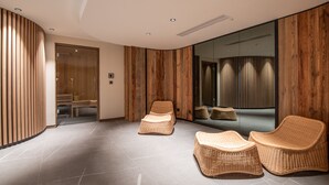 A modern spa room with two wicker chairs, a wooden wall panel, and a large mirror reflecting the room. - Luxury Apartment with Spa Access in Les Allues (Méribel)