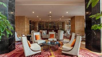 A lobby with seating arrangements, a coffee table, and a patterned carpet.
