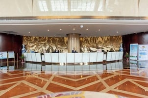 Un área de recepción con diseño moderno, que cuenta con un mostrador central, una pared decorativa y un piso pulido.