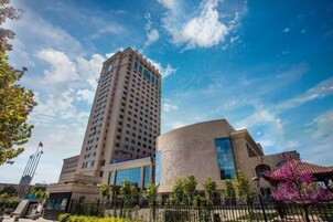 Un edificio alto de diseño moderno, con un gran frente de cristal y una estructura arquitectónica distintiva.