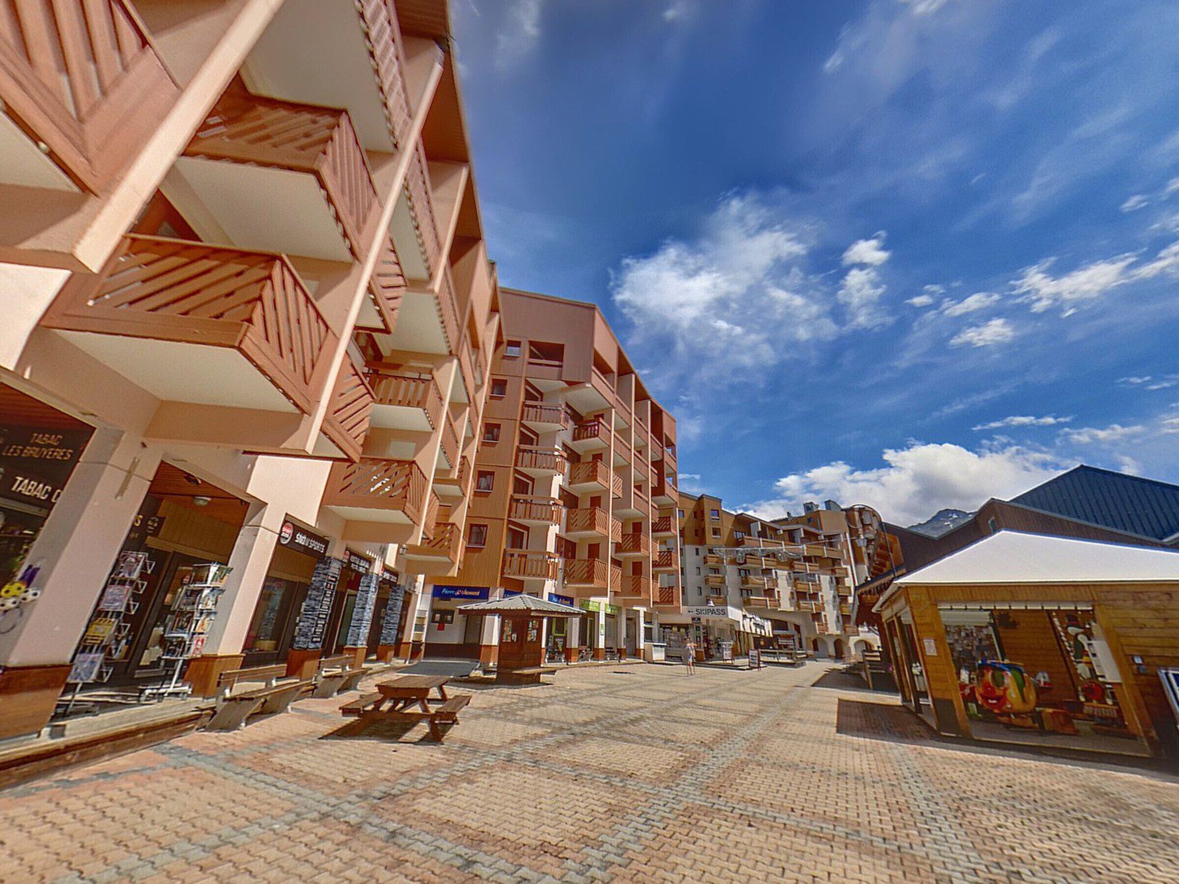 A multi-story building with balconies, a paved courtyard, and various shops.