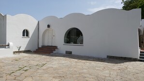 A building with a white exterior, a set of stone steps leading to a white door, and two arched windows. - Villa Sunrise (Lacco Ameno - Forio)