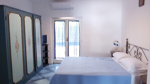 A bedroom with a bed, a wardrobe, a desk, and a window with curtains. - Villa Sunrise (Lacco Ameno - Forio)