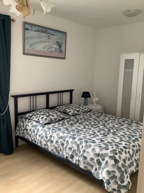 A bedroom with a bed, a nightstand, a lamp, a wardrobe, and a painting on the wall. - Maisonette with small garden on large property (Beychac-et-Caillau)