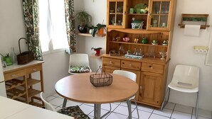 Une cuisine compacte avec une table ronde, des chaises blanches et un meuble en bois doté de portes en verre.