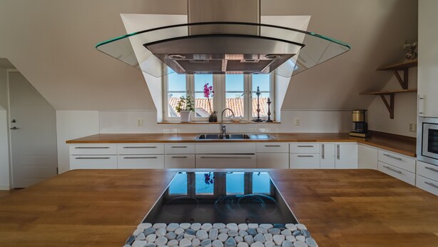 Een moderne keuken met een centraal eiland, witte kasten en een groot raam.
