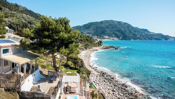A coastal property with a swimming pool, outdoor seating, and a view of the sea.
