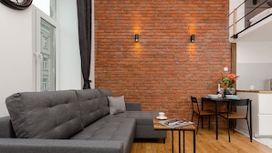 Una sala de estar moderna con un sofá gris, una mesa de centro de madera y una pared de ladrillo.