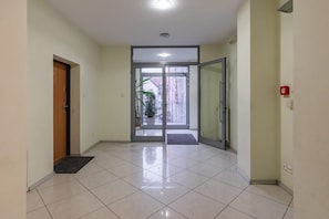 A hallway with a door, a glass door entrance, and a red emergency light.