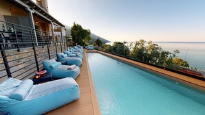 Un área junto a la piscina con múltiples sillas de descanso y vista al mar.