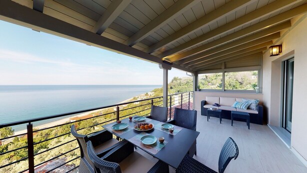 Un balcón con una mesa lista para comer, con vista a la playa y al mar.