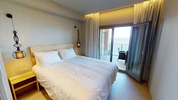 Habitación de hotel con una cama grande, mesitas de noche, una lámpara y vistas al mar a través de un ventanal corredero.