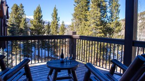 A wooden deck with a table and chairs, overlooking a snowy mountain landscape with tall pine trees. - Luxury Private Home In A Great Location. Hot Tub. (Breckenridge)