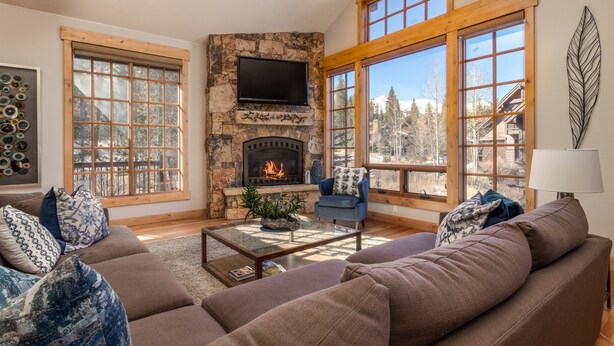 A cozy living room with a stone fireplace, large windows, and comfortable seating. - Luxury Private Home In A Great Location. Hot Tub. (Breckenridge)