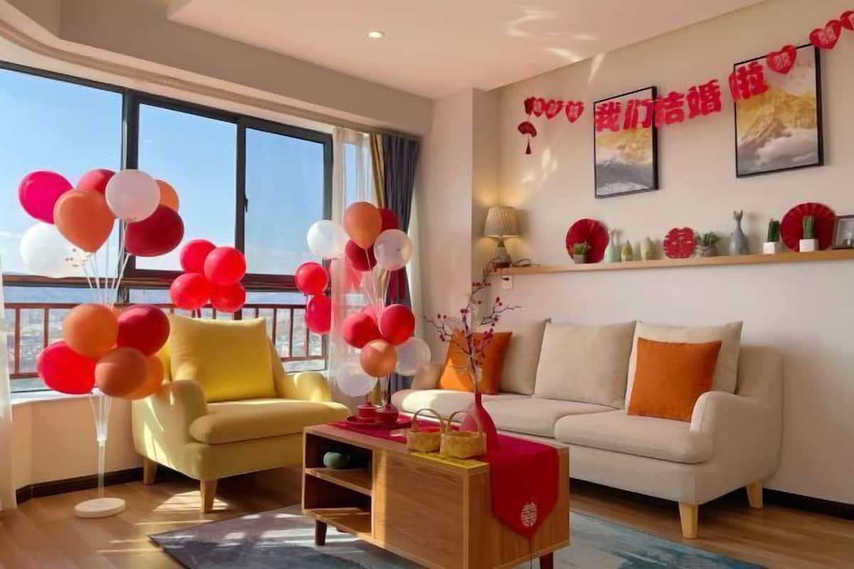 Ein modernes Wohnzimmer mit einer Couch, einem Sessel und einem Couchtisch. Auf dem Couchtisch befinden sich Ballons und eine Vase mit Zweigen.