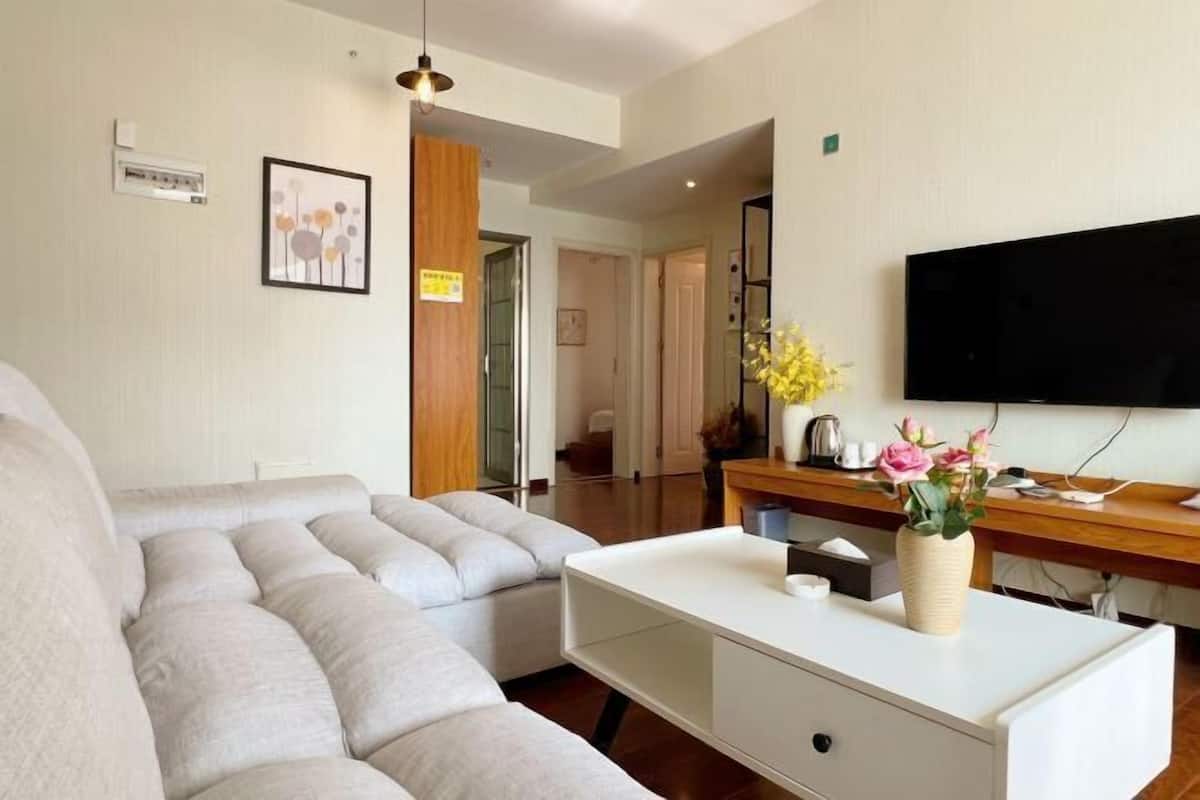 Ein modernes Wohnzimmer mit einem Ecksofa, einem weißen Couchtisch und einem flachbildfernseher an der Wand.