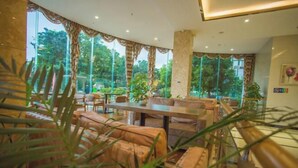 A spacious indoor area with large windows, wooden furniture, and potted plants. - Shilin Slowly Boutique Hotel (Shilin)