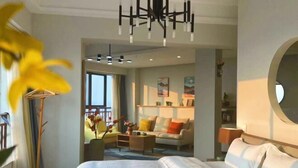 A modern hotel room with a large bed, a seating area with a sofa and armchairs, a coffee table, and a dining table. There is a large window providing natural light and a view of the outdoors. - Shilin Slowly Boutique Hotel (Shilin)
