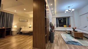 A modern hotel room with a wooden floor, a bed, a desk, a sofa, and a large window with a view. - Shilin Slowly Boutique Hotel (Shilin)