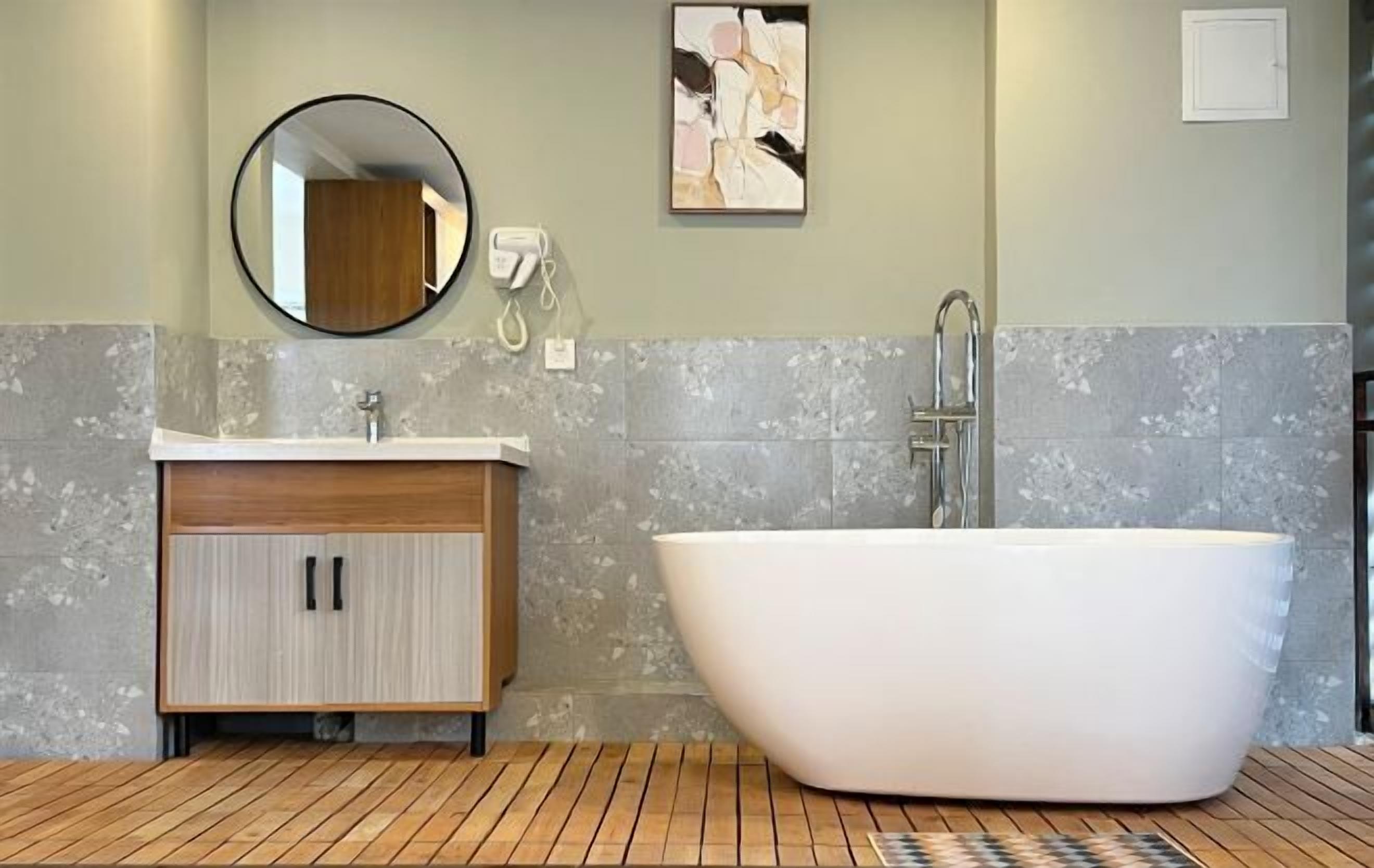 A modern bathroom with a freestanding bathtub, a wooden vanity with a mirror, and a wall-mounted telephone.
