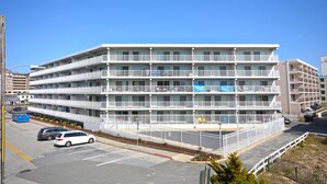 Ein mehrstöckiges Hotel mit Balkonen, einem Parkplatz und einem eingezäunten Bereich.