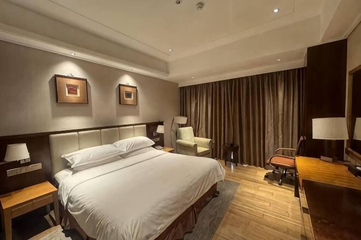 Una habitación de hotel con una cama grande, mesitas de noche, un escritorio y una silla.