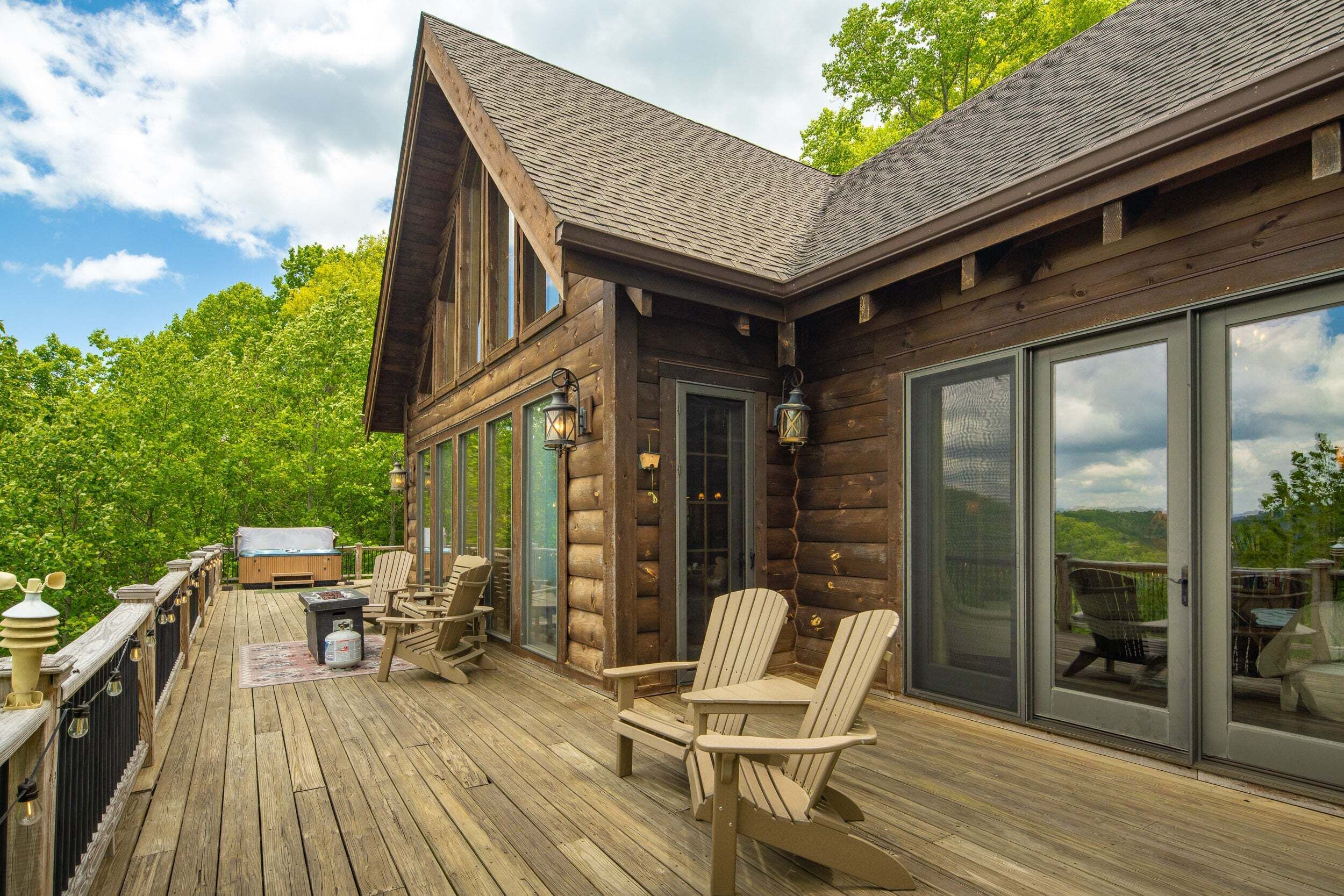 A wooden deck with Adirondack chairs, a grill, and a hot tub.