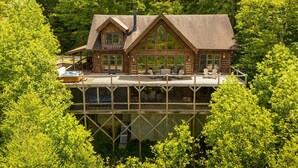 A log cabin with a deck, large windows, and a chimney. - Elegant Home with Incredible Views (Banner Elk)
