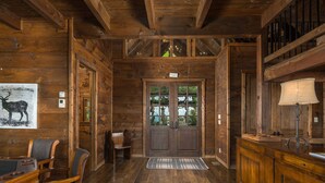 A wooden interior with a double door, a bench, a table with chairs, and a lamp. - Elegant Home with Incredible Views (Banner Elk)