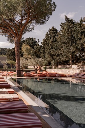 A pool area with lounge chairs and a large tree.