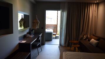 Una habitación de hotel moderna con una cama, un escritorio, una silla, un televisor y vistas al balcón exterior.
