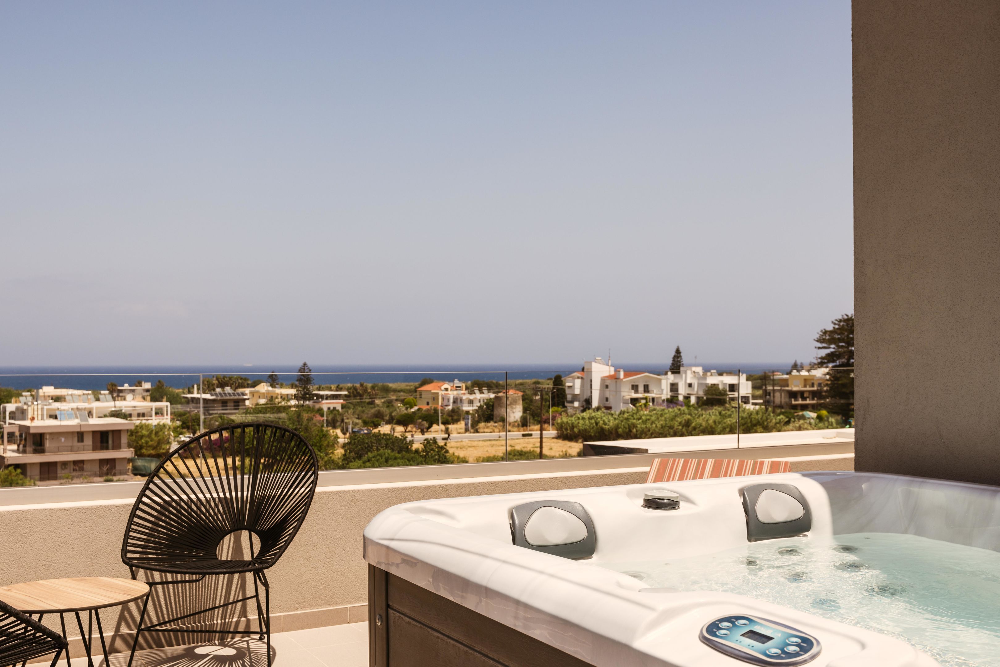 Varanda com hidromassagem, cadeira e mesa, com vista para a costa.