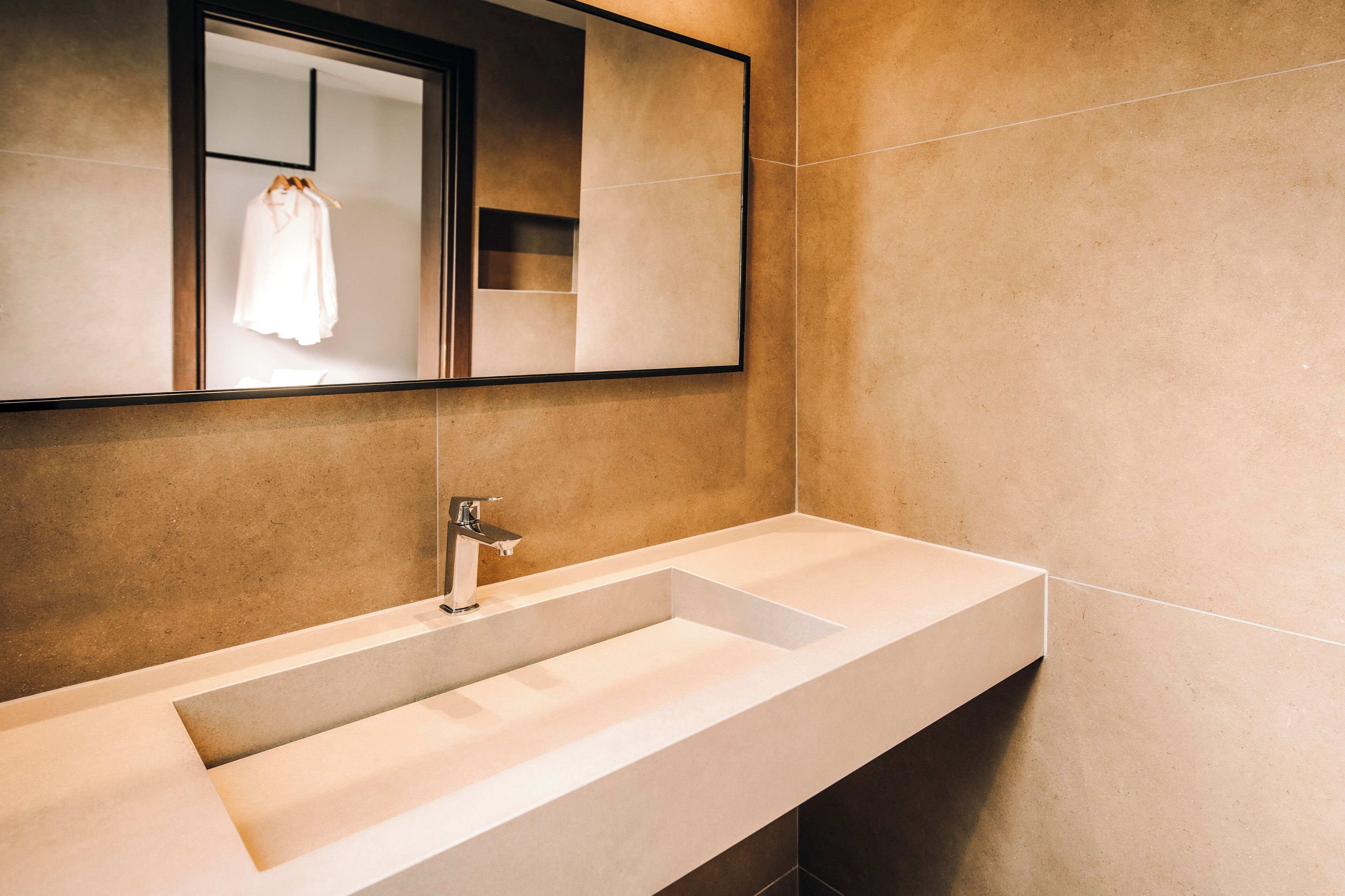 Une salle de bain moderne avec un grand miroir, un lavabo blanc et un porte-serviettes.