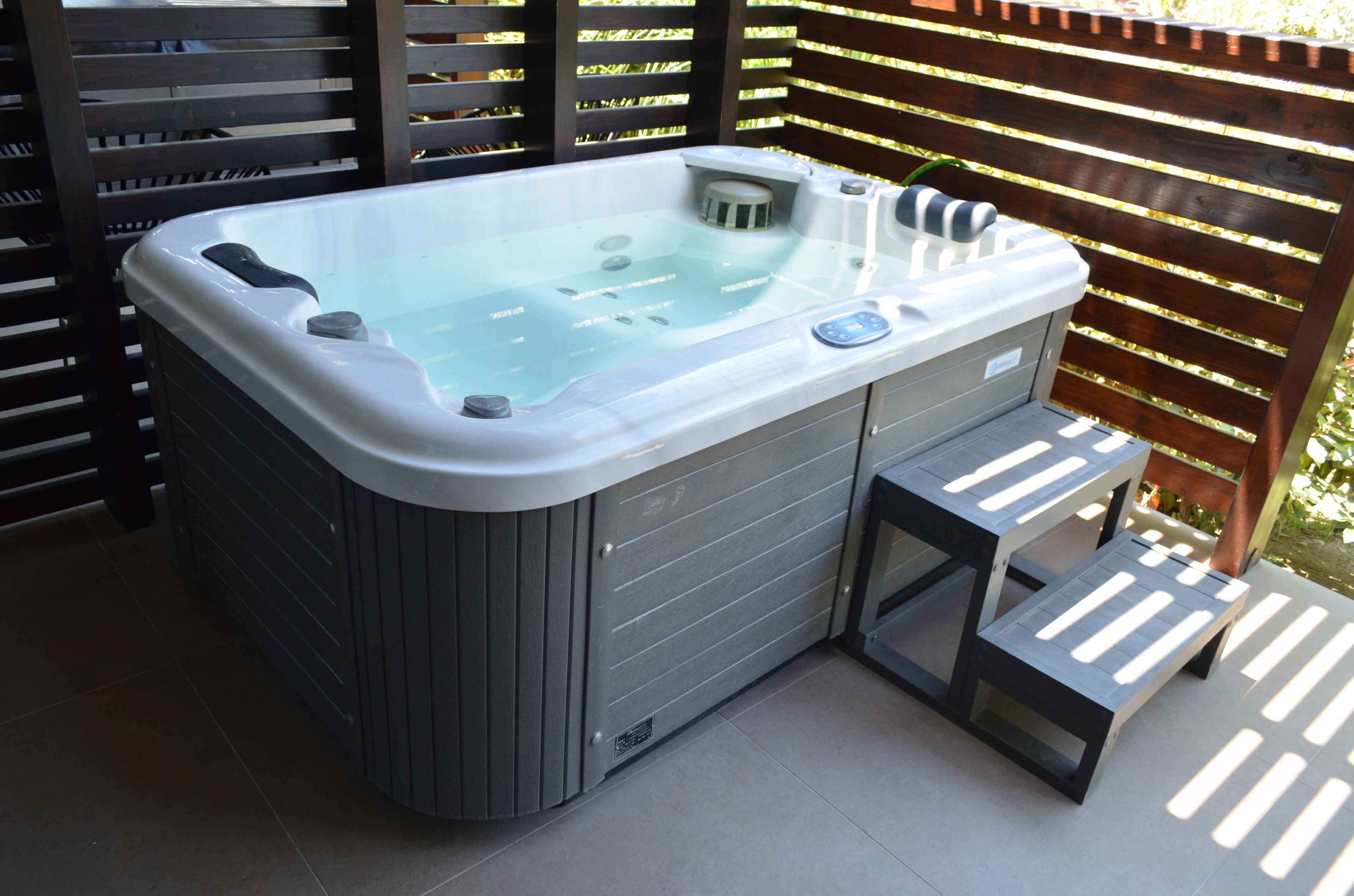 Een jacuzzi met bedieningspaneel en een opstapje.