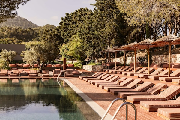 Una piscina al aire libre, sombrillas, sillones reclinables de piscina