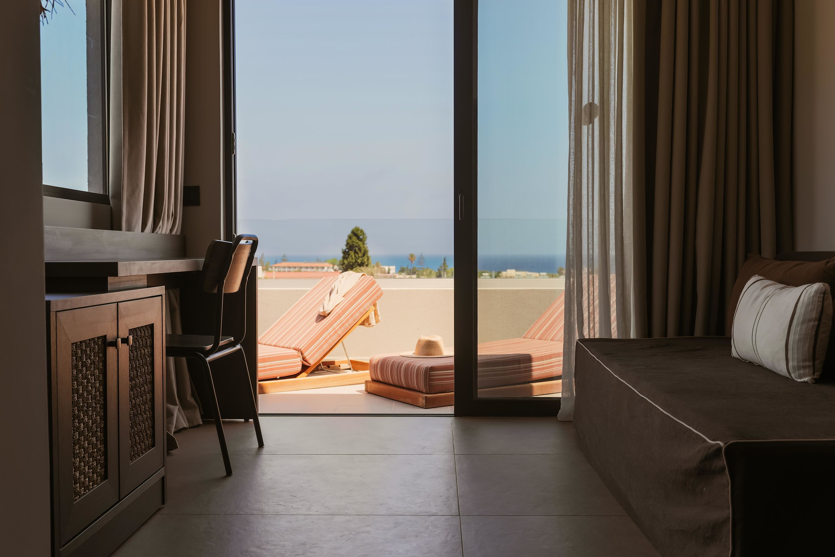 A room with a bed, a desk, and a view of the beach.