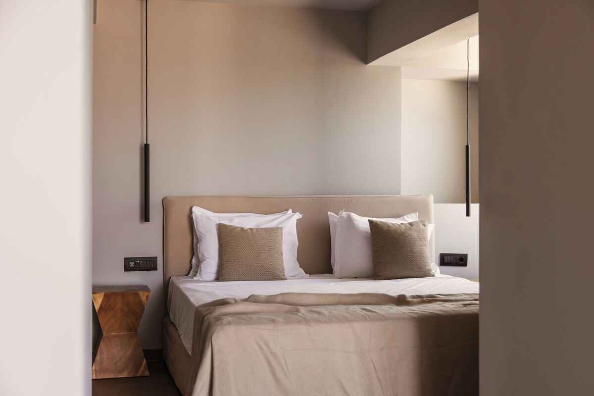 A modern hotel room with a large bed, two bedside tables, and a nightstand.