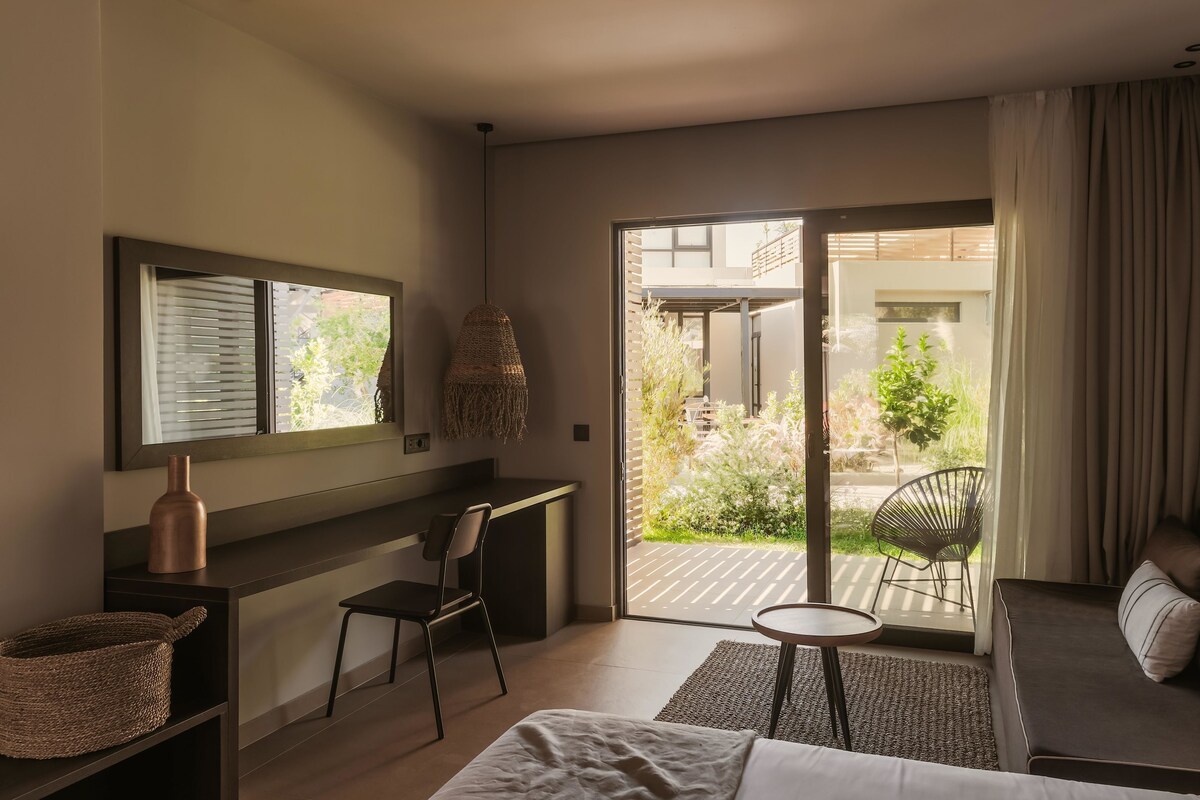 A modern bedroom with a bed, desk, and seating area.