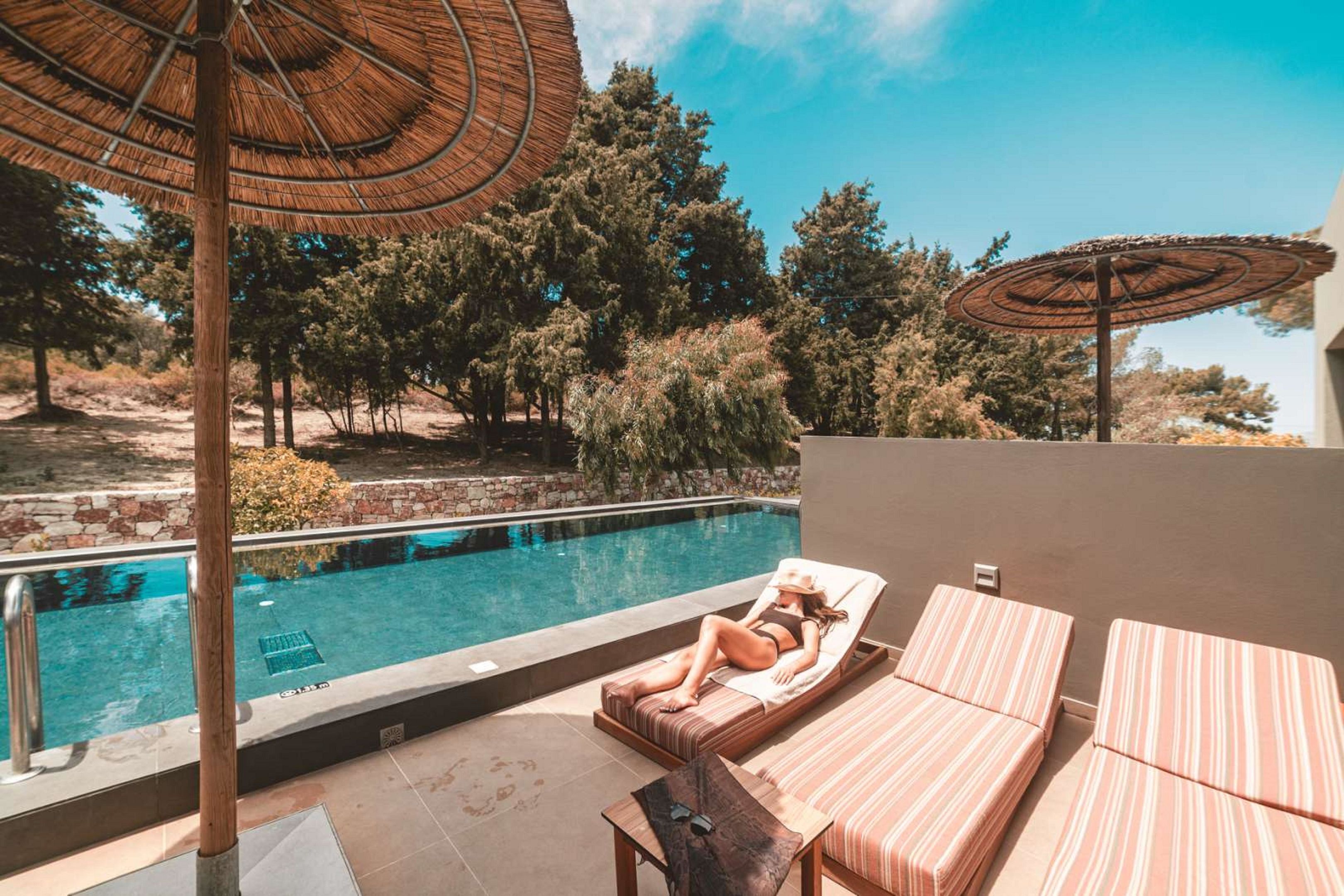 A poolside area with lounge chairs, a pool, and umbrellas.