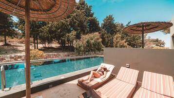 A poolside area with lounge chairs, a pool, and umbrellas.
