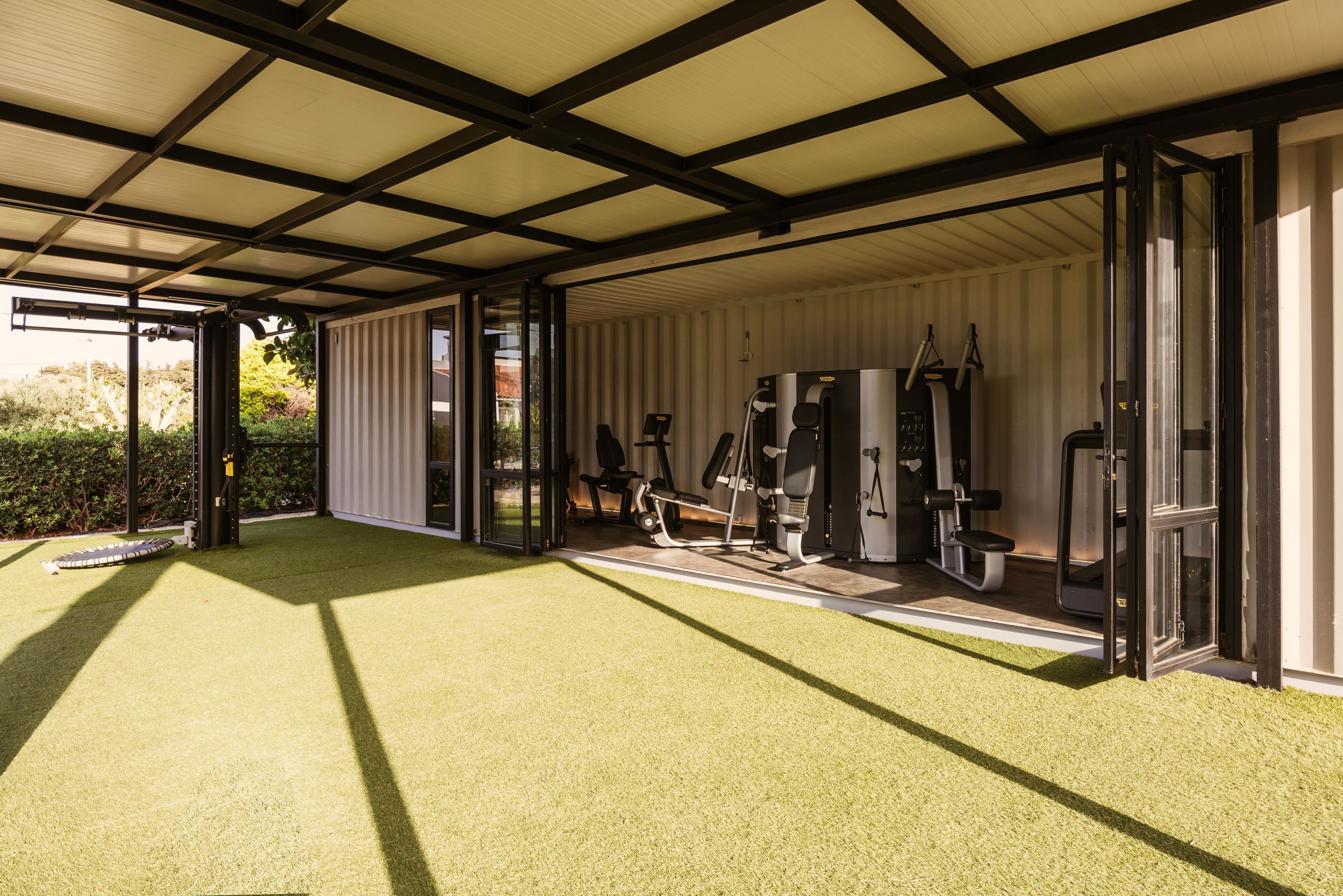 An indoor gym with exercise equipment, a green artificial turf floor, and a large open space with a high ceiling.