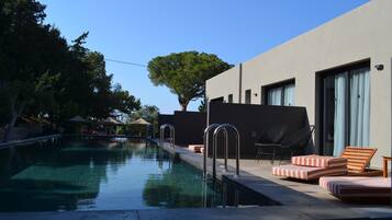 Ein moderner Poolbereich mit klarem Wasser, Liegestühlen und einer Pergola.