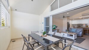 Une cuisine moderne avec des armoires blanches, un four encastré et un coin repas comprenant une table et des chaises en verre.