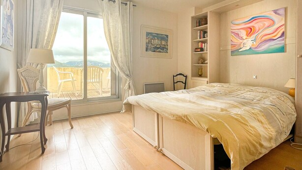 A bedroom with a bed, a chair, a desk, a window with curtains, a bookshelf, and a painting. - Beautiful Villa 8 guests - Pool Access in Mandelieu (Mandelieu-la-Napoule)